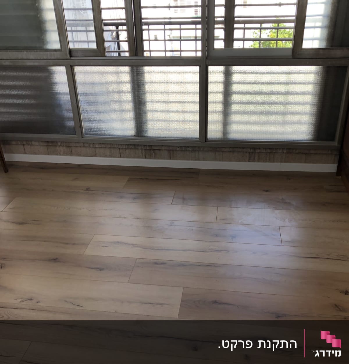 רצפת פרקט עץ בהירה בחדר עם חלון גדול